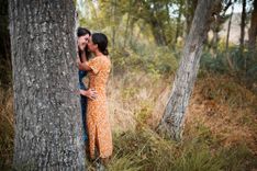 2 Frauen, die sich hinter einem Baum küssen
