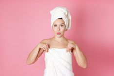 Frau in Handtuch gewickelt vor pinkem Hintergrund