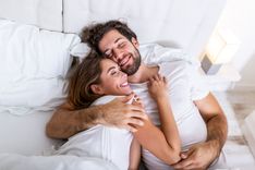 Schönes Liebespaar küsst sich im Bett. Schönes junges Paar liegt zusammen auf dem Bett. Romantisches junges Liebespaar auf dem Bett liegend. Schönes Paar lächelnd im Bett.
