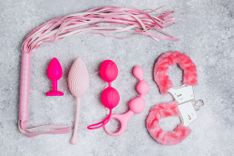 Verschiedenes pinkes Sexspielzeug auf grauem Hintergrund