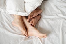 Zwei paar Füße ragen unter einer Bettdecke hervor