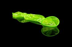 Abgestreiftes grünes Kondom auf schwarzem Hintergrund