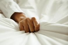 Hand, die sich in eine Bettdecke krallt