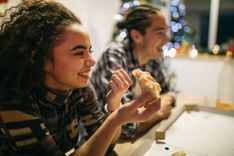 Eine Frau, die Pizza isst und lacht an einem holzfarbenen Tisch