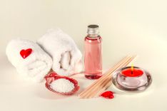 Handtücher, Holzstäbchen, Massageöl und Massagekerze auf beigem Hintergrund