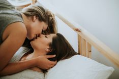 2 Frauen liegen im Bett und küssen sich