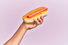 Symbolbild wichsen: Frau hält einen Hotdog in der Hand