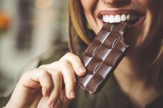 Frau beißt von einer Tafel Schokolade ab