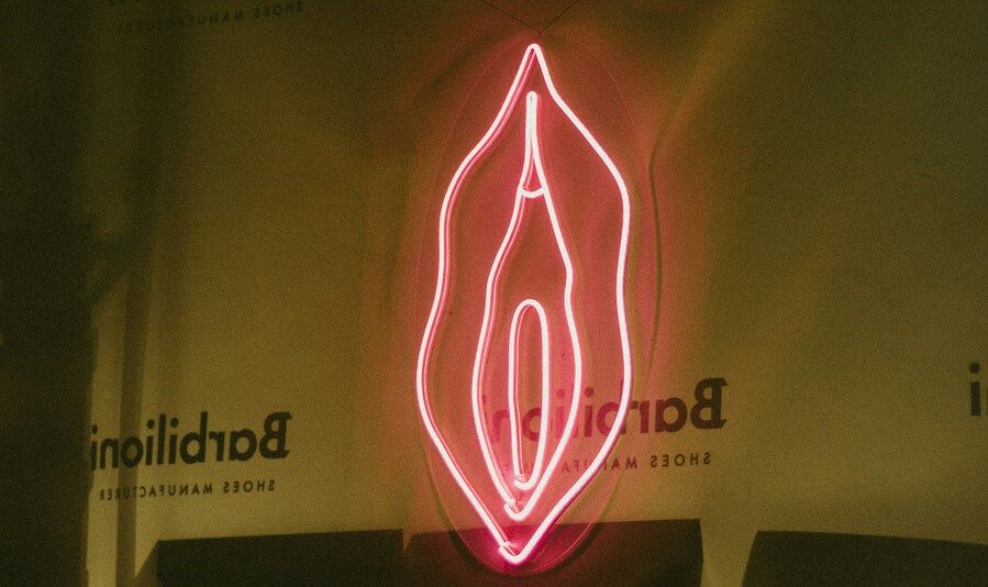 Ein rotes Neonschild hat die Form einer Vulva