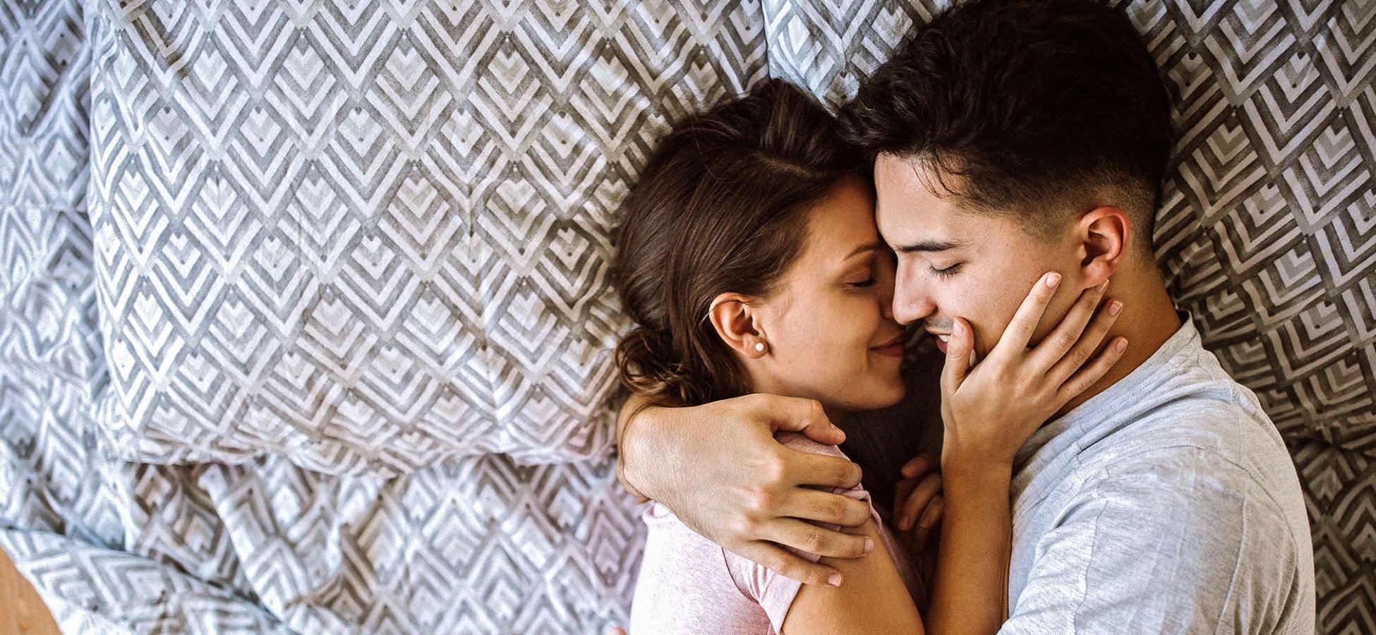 Mann und Frau liegen im Bett und umarmen sich liebevoll