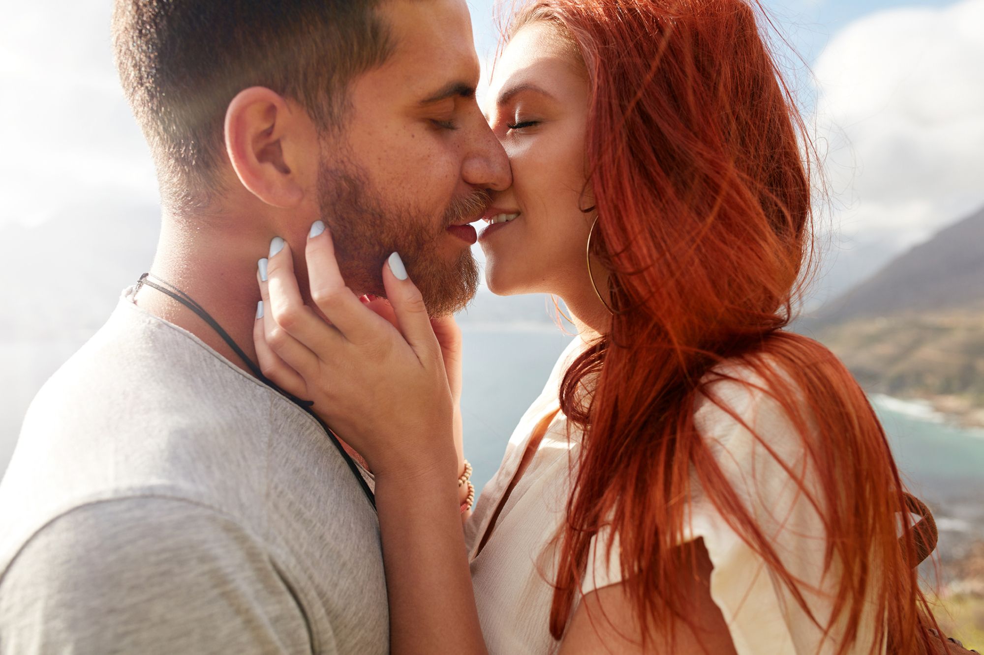 Mann und Frau küssen sich vor einer Landschaft